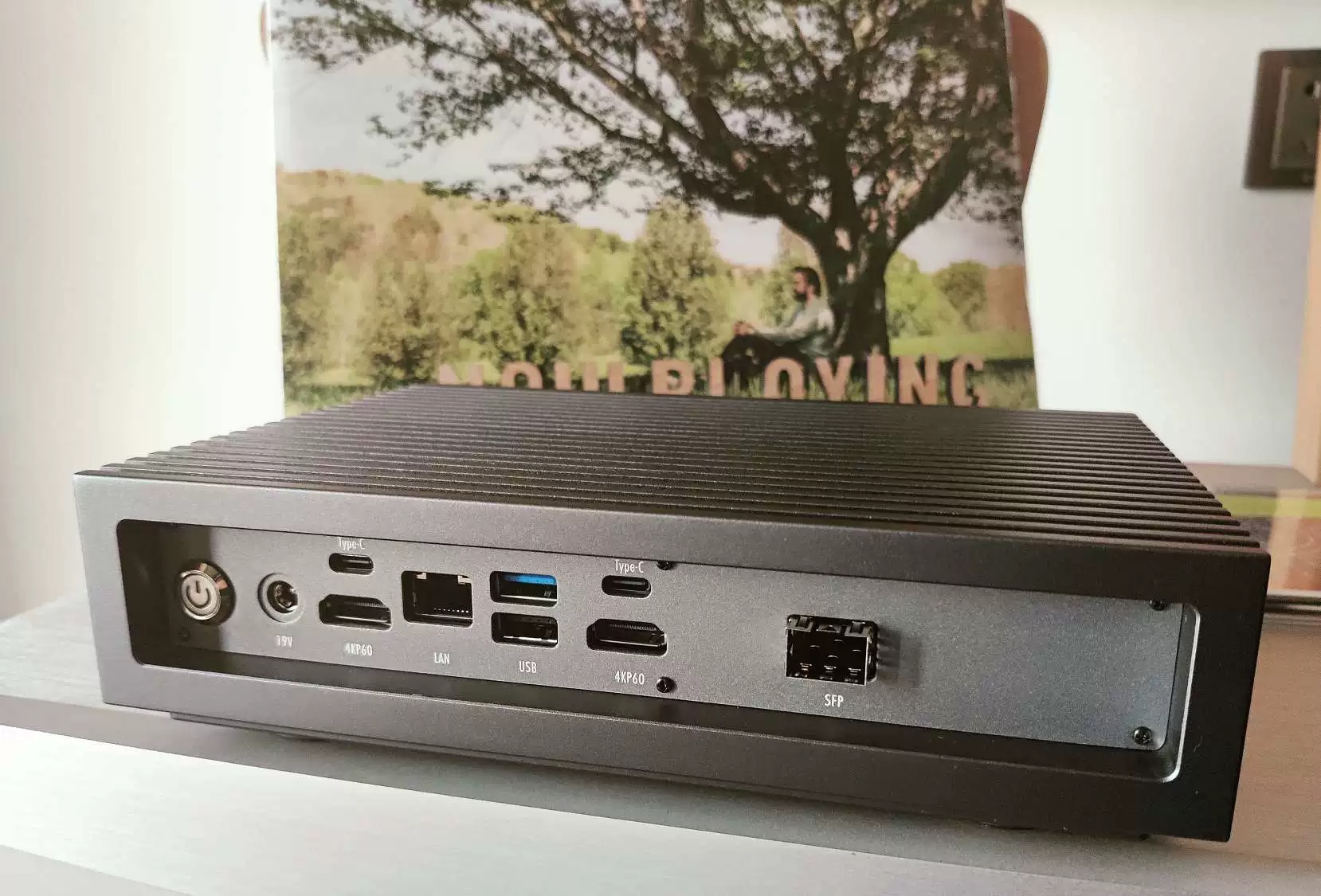 脑 Brain13 背部面板实拍：19V 电源、双 HDMI、LAN、USB、Type-C 与 SFP 光口一字排开，背景立着一张黑胶唱片
